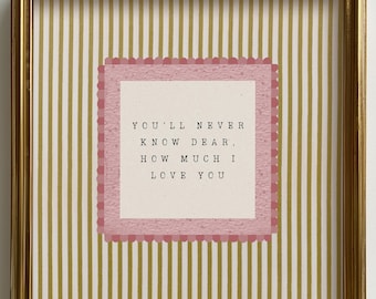 May include: A framed print with a gold-colored frame. The print features a pink and white striped background with a pink scalloped border around a white square. The text reads: "YOU'LL NEVER KNOW DEAR, HOW MUCH I LOVE YOU."