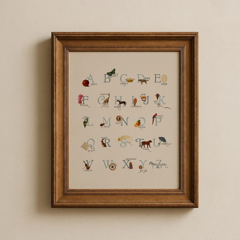 May include: Framed alphabet print featuring whimsical illustrations for each letter. The artwork includes a red apple, a butterfly, a crown, a dog, and an egg. The print is in a wooden frame, perfect for a child's room or nursery.