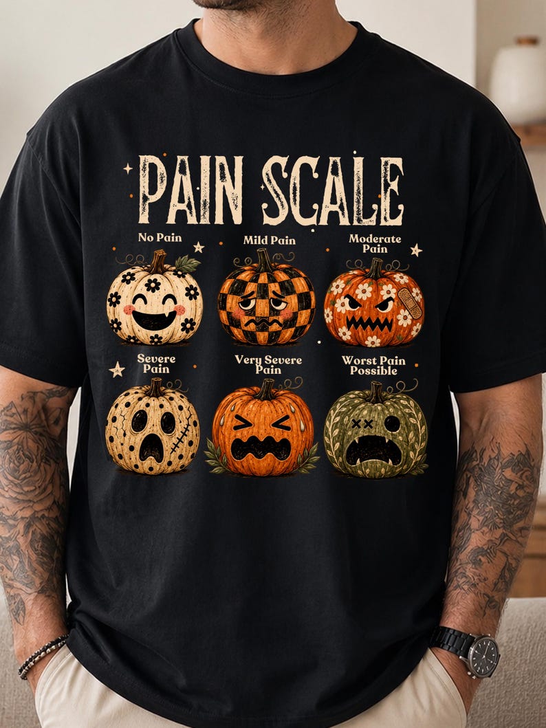 May include: A black t-shirt featuring a graphic titled PAIN SCALE with six pumpkins showing different expressions. The pumpkins are labeled No Pain, Mild Pain, Moderate Pain, Severe Pain, Very Severe Pain, and Worst Pain Possible with various patterns.