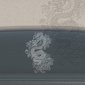 May include: A white vinyl decal featuring a detailed line art illustration of a coiled dragon intertwined with a large chrysanthemum flower. The design is applied to a dark, smooth surface, showcasing intricate scales and floral petals.