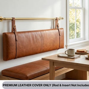 Könnte beinhalten: Eine braune Leder-Banklehne hängt an einer Messingstange mit Lederriemen. Die Banklehne ist rechteckig und hat ein genähtes Design. Der darunter liegende Sitz ist ebenfalls aus braunem Leder. Der Text unten lautet "PREMIUM LEATHER COVER ONLY (Rod & Insert Not Included)".