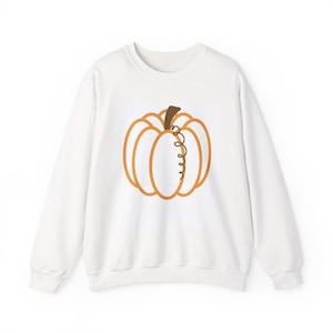 Könnte beinhalten: Ein weißes langärmeliges Sweatshirt mit Rundhalsausschnitt und einer mittigen Grafik eines orangefarbenen Kürbisses mit braunem Stiel und einem einzelnen, geschwungenen Rankendetail. Das Kürbisdesign ist orange umrandet und weiß segmentiert.