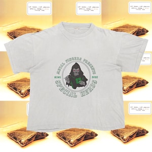 May include: White t-shirt with a graphic of a hooded figure with red eyes, the text "METAL FINGERS PRESENTS" and "KING SIZE SPECIAL HERBS" in a circular design. Small packages with text surround the shirt.