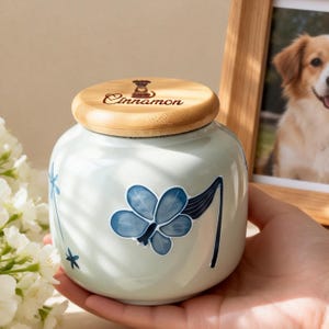 May include: A white ceramic mug with a black handle and the text "But First, Coffee" in a black, bold font. The mug is on a white surface.