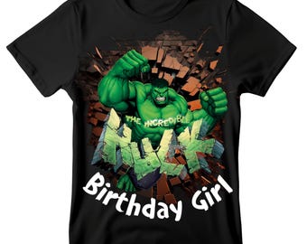 May include: Black t-shirt with a graphic of the Incredible Hulk bursting through a wall. The Hulk is green, with the text "Hulk" and "Birthday Girl" in white. The shirt has a crew neck.