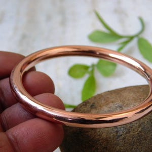 Peut inclure: Un bracelet jonc en cuivre poli. Le bracelet rond a une surface lisse et réfléchissante. La couleur cuivre est une teinte brun-rougeâtre chaude. Le jonc est un bijou simple et élégant.