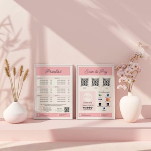 Op de afbeelding: Twee ingelijste roze en witte borden met de tekst "Pricelist" en "Scan to Pay". Het bord "Scan to Pay" toont QR-codes en betalingsopties. Een witte vaas met bloemen en een vaas met tarwearen zijn ook aanwezig.
