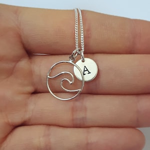以下が含まれることがあります： 波のチャームとAの文字が刻まれた小さな丸いチャームが付いたシルバーネックレス