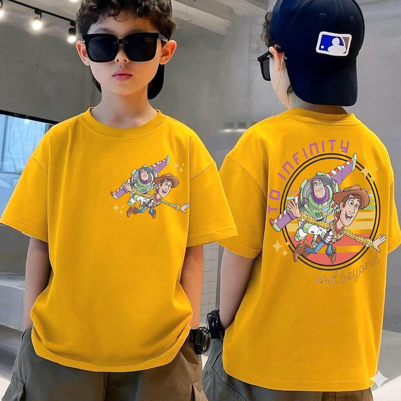 May include: Yellow t-shirt featuring a cartoon graphic of Buzz Lightyear and Woody. The front of the shirt shows the characters flying, while the back has a circular design with the words "TO INFINITY AND BEYOND".