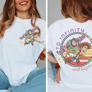 May include: White t-shirt featuring a colorful graphic of Buzz Lightyear and Woody from Toy Story. The front has a small image of the characters, while the back displays a larger image with the text "TO INFINITY and beyond."