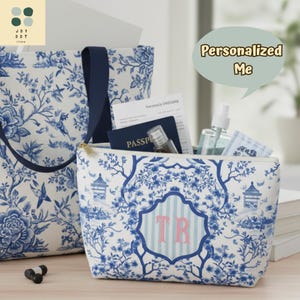 Könnte beinhalten: Eine weiße und blaue Tragetasche und Kosmetiktasche mit Toile-de-Jouy-Muster. Die Kosmetiktasche hat einen goldenen Reißverschluss und ein Monogramm mit den Buchstaben "TR". Die Tragetasche hat einen marineblauen Griff.