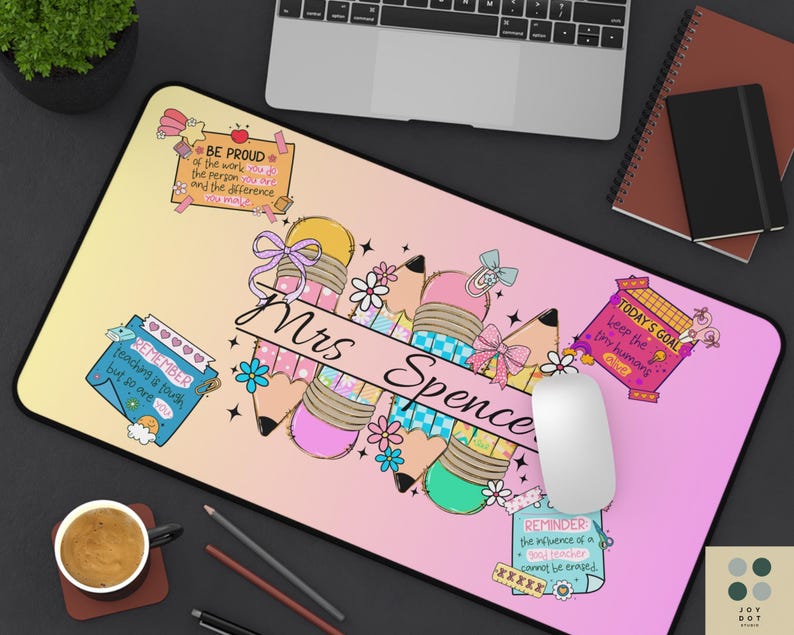 May include: A personalized mousepad with a gradient background of yellow and pink. It features a pencil design with the name "Mrs Spence" and inspirational quotes. A white mouse and other office supplies are visible.