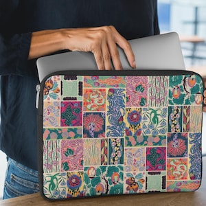 May include: A laptop sleeve with a colorful patchwork design. The pattern features various floral and abstract motifs in shades of pink, green, blue, and orange. The sleeve has a black zipper and a black border.