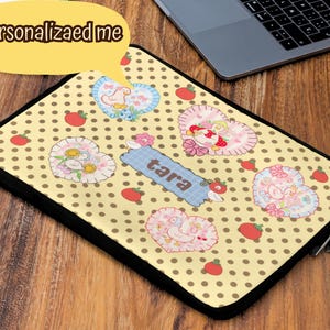May include: Laptop sleeve with a yellow polka dot pattern, featuring heart-shaped designs with floral and bird motifs, and the name "Tara". The sleeve has a black border and a zipper closure. Text on the image says "Personalized me".
