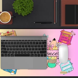 May include: A desk mat with a colorful design featuring the text "BE PROUD", "TODAY'S GOAL", and "REMINDER". The mat has a laptop, mouse, and other office supplies on top. The mat is approximately 30 inches long.