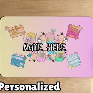 May include: Personalized mousepad with a pastel gradient background. The design features pencils with bows and flowers, and text that says "NAME HERE". Additional text includes "BE PROUD", "TODAY'S GOAL", and "REMEMBER".