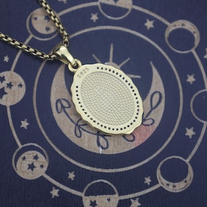 May include: A gold-toned oval pendant necklace featuring a textured, stippled center and a scalloped edge. The back of the pendant is clearly stamped with the text S925, indicating its composition. The pendant hangs from a matching gold-toned box chain.