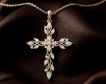 May include: A gold cross pendant necklace featuring a delicate vine-like structure adorned with numerous marquise-cut and round-cut clear gemstones. The pendant is suspended from a thin gold chain, showcasing an intricate, symmetrical design.