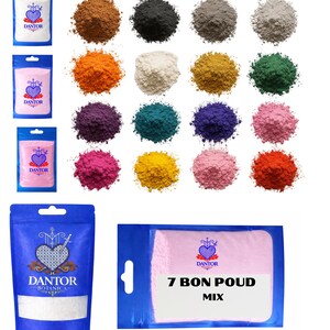 May include: An assortment of colorful powders and packaged products. The powders are in various shades, including brown, black, gray, orange, white, yellow, green, purple, teal, blue, pink, and red. The packages feature the "DANTOR" logo and the text "7 BON POUD MIX".