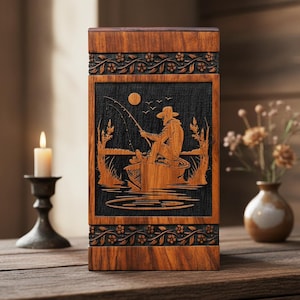 May include: A wooden box with a detailed carving of a fisherman in a boat, set against a dark background. The box is framed with floral patterns and has a natural wood grain finish. The design includes a moon, birds, and water.