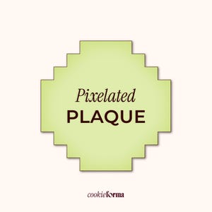 以下が含まれることがあります： 「Pixelated PLAQUE」の文字がダークブラウンで書かれた、ピクセル化されたライトグリーンのプラーク。プラークはピクセル化されたエッジを持ち、クリーム色の背景に配置されています。cookieformaのロゴが下にあります。