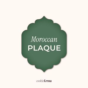 May include: A green plaque with a decorative scalloped edge, featuring the words "Moroccan PLAQUE" in white. The background is a light beige color, with the brand name "cookieforma" at the bottom.