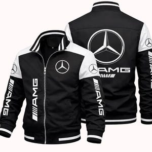 Könnte beinhalten: Schwarz-weiße Jacke mit Reißverschluss und AMG-Logo und -Schriftzug. Die Jacke hat weiße Akzente an Schultern, Kragen und Bündchen. Das AMG-Logo ist prominent auf der Vorder- und Rückseite zu sehen. Eine sportliche, lässige Jacke.