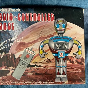 Puede incluir: Robot Radio Shack con control remoto vintage. El robot es plateado, rojo y azul, con un mando a distancia. La caja dice "Robot con control remoto" y "¡Más de 0,9 m de altura!"