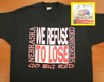 Könnte beinhalten: Schwarzes T-Shirt mit rotem und weißem Text, der "Nebraska Cornhuskers We Refuse To Lose Go Big Red" lautet. Das Shirt ist von der Marke Fruit of the Loom.