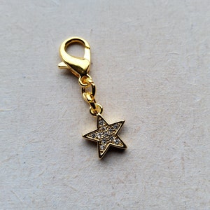 May include: A gold-tone star charm with clear rhinestones, attached to a gold-tone chain and a lobster clasp.