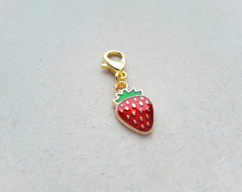 May include: Gold-toned charm with a red and green enamel strawberry design. The charm has a lobster claw clasp.