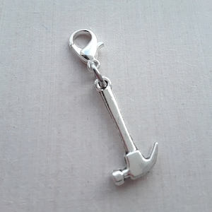 May include: Silver charm in the shape of a hammer with a silver lobster clasp.
