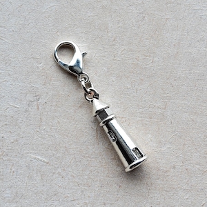 May include: Silver charm in the shape of a lighthouse with a silver lobster claw clasp.