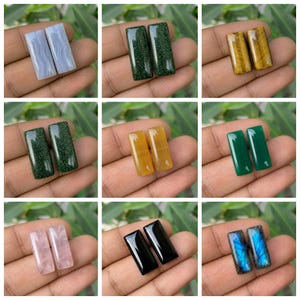 Puede incluir: Una colección de nueve pares de piedras preciosas cabujón rectangulares en varios colores y texturas, incluyendo ágata de encaje azul, aventurina verde, ojo de tigre, jade amarillo, jade verde sólido, cuarzo rosa, ónix negro y labradorita azul.