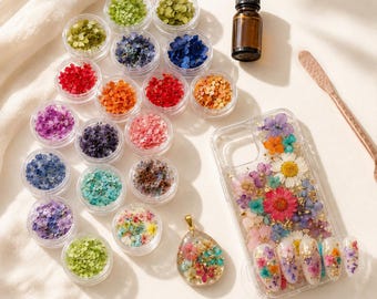 May include: A collection of colourful dried flowers in small clear containers, a brown bottle, a clear phone case, a pendant, and nail art, all with floral designs. The flowers are in shades of red, orange, purple, blue, and green.