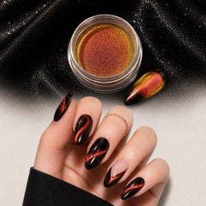 Puede incluir: Un tarro de polvo de uñas iridiscente con un efecto de cambio de color rojo y dorado. La imagen también muestra una mano con uñas largas y ovaladas pintadas de negro con un efecto ojo de gato rojo. Se muestra una sola uña por separado.