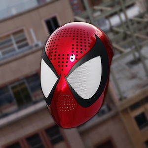 Op de afbeelding: Een rood en zwart Spider-Man-masker met witte mesh oogbedekkingen. Het masker heeft een glanzende afwerking en is aan de bovenkant geperforeerd met kleine gaatjes. De oogopeningen zijn zwart omlijnd.