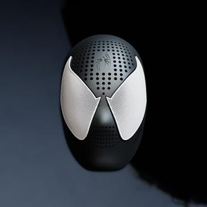 May include: Black and white Spider-Man mask-shaped speaker. The mask has white mesh eye coverings and a spider emblem on the top. The speaker has a perforated design for sound.