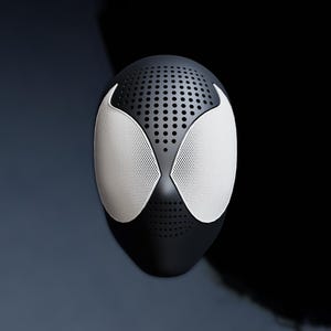 May include: A black mask with white mesh eye coverings and a perforated top. The mask has a sleek, modern design, with a smooth, matte finish. The eye coverings are shaped like stylized spider eyes.