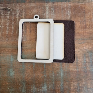 May include: Two wooden frames, one with a brown backing, are stacked on top of each other. The frames are rectangular and have a simple design.