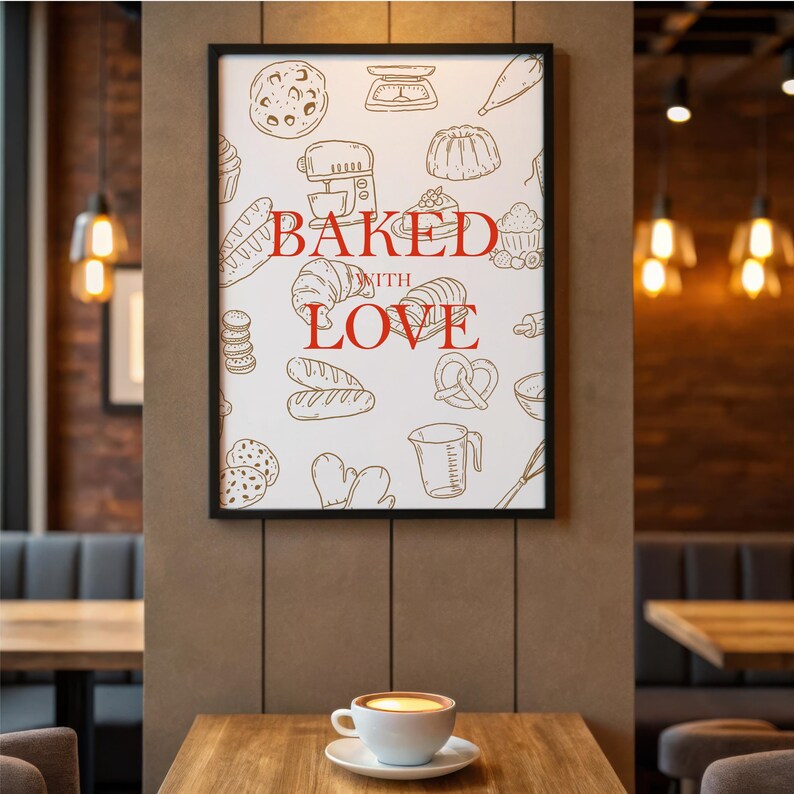 May include: A framed print with a black border featuring a white background and red text that reads "Baked with Love." The print is decorated with line drawings of baked goods and kitchen tools. A cup of coffee sits on a wooden table.