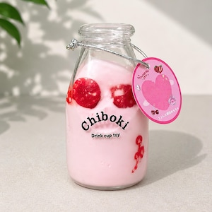 May include: A clear glass bottle filled with pink liquid and red circular accents. The bottle features the black text Chiboki Drink cup toy. A silver string attaches a round pink tag with a heart graphic, strawberry, and cherry illustrations.