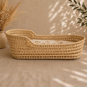 Puede incluir: Cuna tejida en color beige natural. La cuna tiene una forma curva con un dise&ntilde;o tejido y un forro interior de tela con estampado floral. La cuna est&aacute; dise&ntilde;ada para un beb&eacute;.