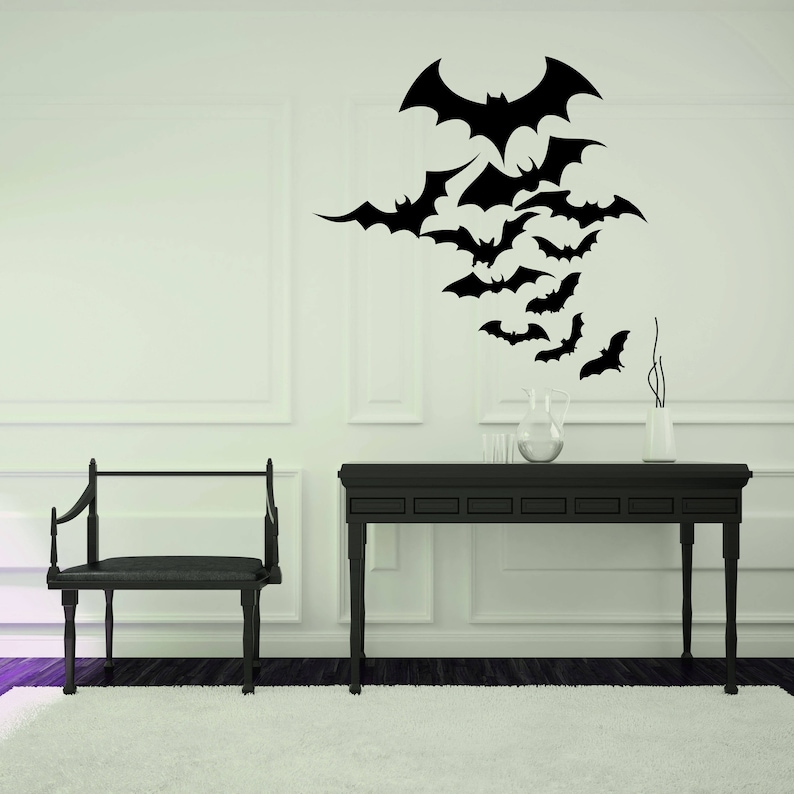 May include: A black console table with a white wall behind it. A black and white wall decal of bats is on the wall. A black chair is in front of the table.