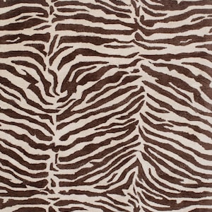 May include: A close-up of a rug with a zebra stripe pattern. The rug features alternating stripes of brown and off-white, creating a bold and striking design. The rug's texture appears soft and inviting, suitable for home decor.