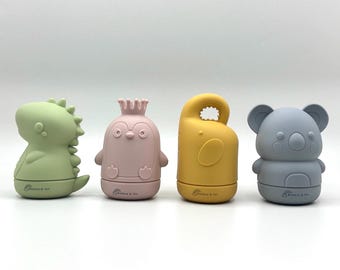 May include: Four pastel-coloured silicone bath toys for babies, shaped like a dinosaur, penguin, handle, and koala. The toys are green, pink, yellow, and grey. Each toy has the text "Bubble & Ivy" printed on the base.