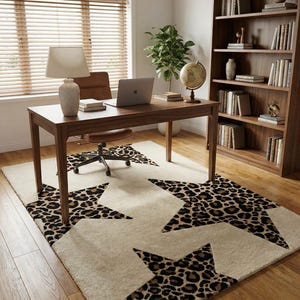 May include: A home office setup featuring a wooden desk with a laptop, lamp, and books. A cream-colored rug with large leopard print star designs sits beneath the desk and a rolling chair. A wooden bookshelf and globe are also visible.