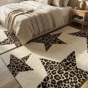 May include: Cream-colored star-shaped rugs with a leopard print design. The rugs are placed on a wooden floor in front of a bed with neutral-toned bedding. The room has a cozy, inviting atmosphere.