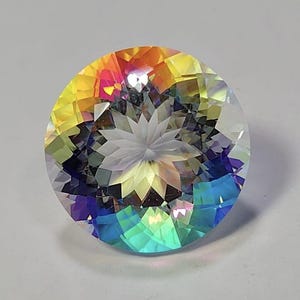 Peut inclure: Une pierre précieuse ronde à facettes avec une finition irisée vibrante. La surface affiche un spectre de couleurs comprenant le jaune, l'orange, le rose, le violet et le bleu, avec un motif central en étoile créé par des coupes géométriques.