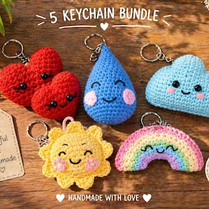 Può includere: Una collezione di cinque portachiavi all'uncinetto fatti a mano, tra cui cuori rossi, una goccia di pioggia blu, una nuvola blu, un sole giallo e un arcobaleno. I portachiavi hanno facce sorridenti e sono attaccati ad anelli di metallo. Il testo "5 KEYCHAIN BUNDLE" è incluso.